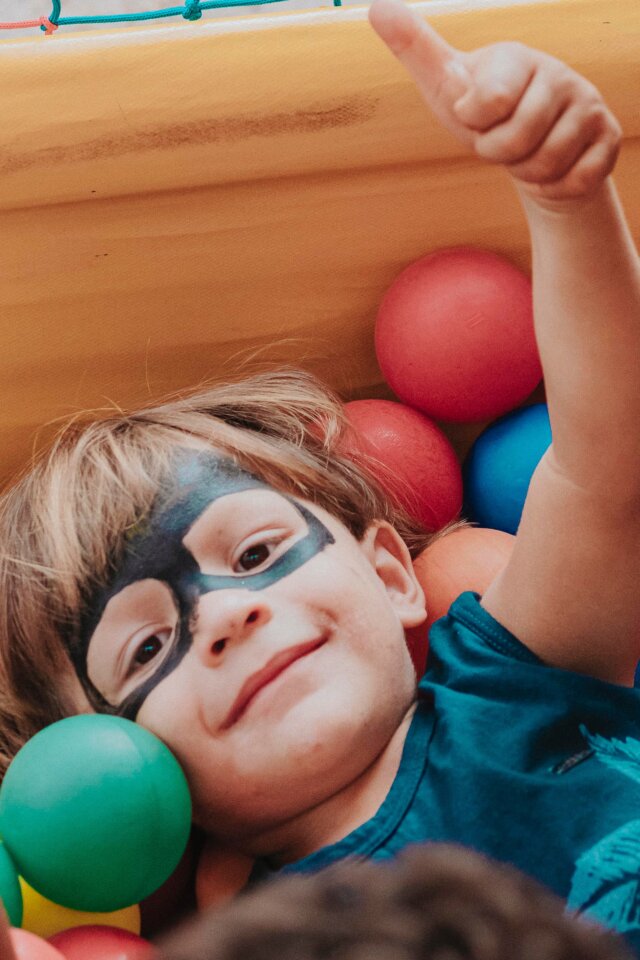a happy preschooler playing in a ball pit